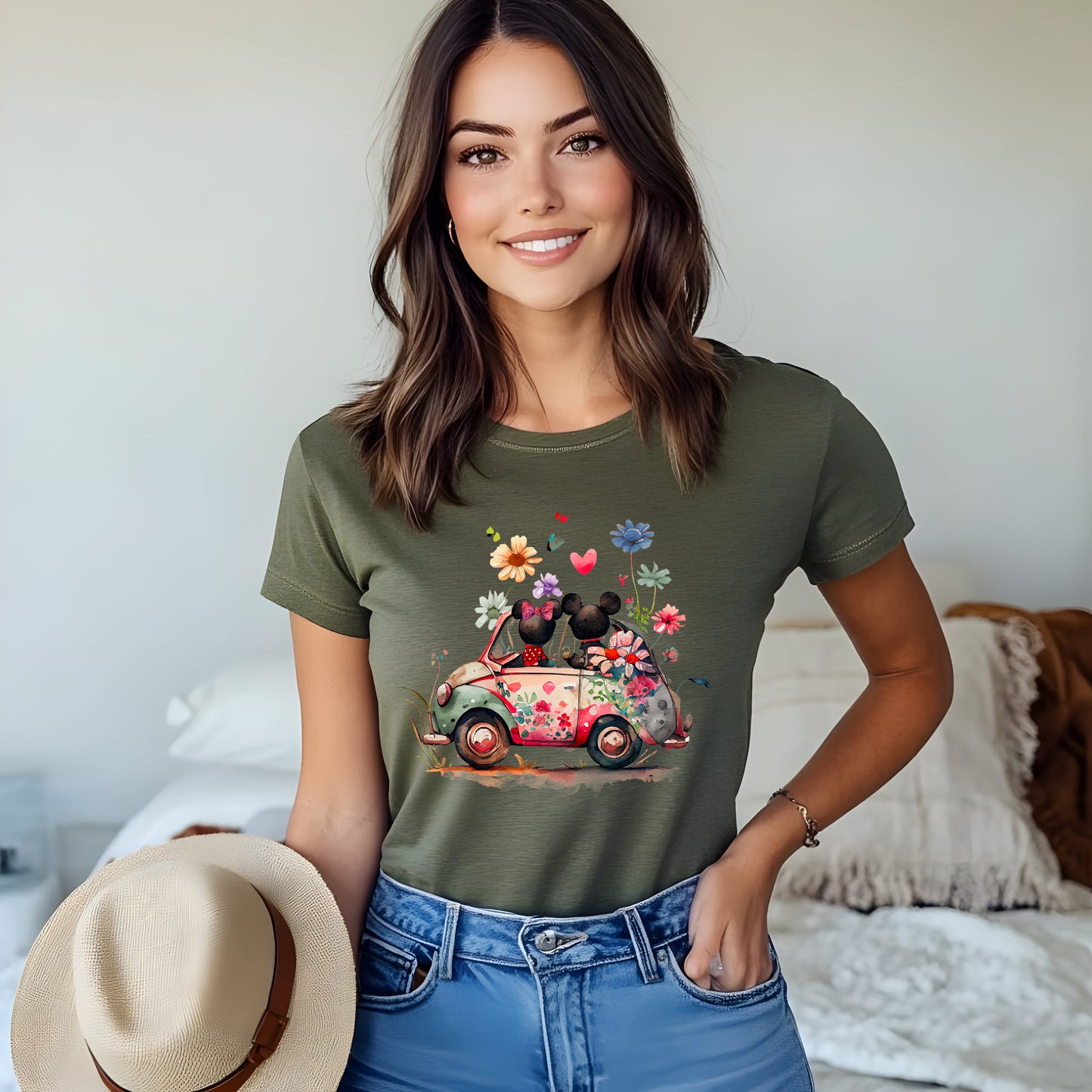A women wearing olive unisex t-shirt featuring an artwork of Mickey and Minnie Mouse in a car surrounded by flowers.