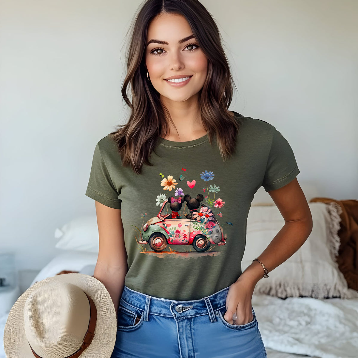 A women wearing olive unisex t-shirt featuring an artwork of Mickey and Minnie Mouse in a car surrounded by flowers.