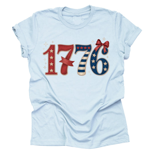 A light blue unisex short-sleeve T-shirt with a patriotic 1776 print and a bow design.