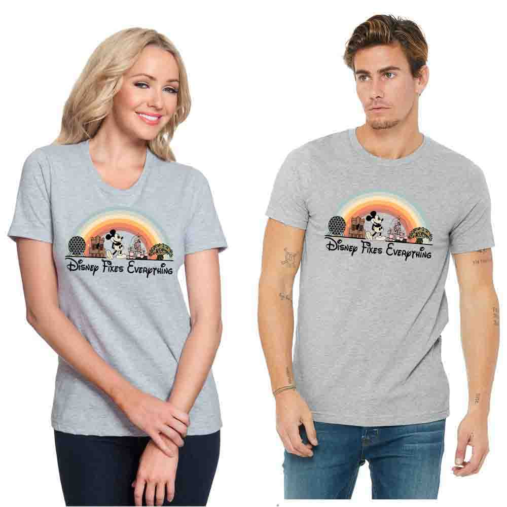 Models wearing gray short sleeve unisex t-shirt with a graphic that includes Disney park icons and the text 'Disney Fixes Everything' in a rainbow-colored arch.
