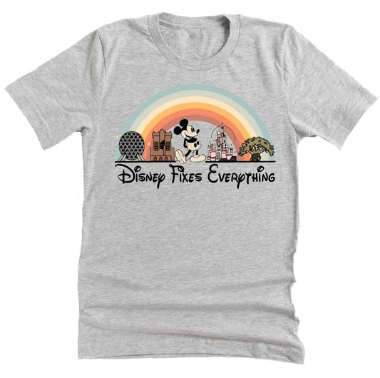 A gray short sleeve unisex t-shirt with a graphic that includes Disney park icons and the text 'Disney Fixes Everything' in a rainbow-colored arch.