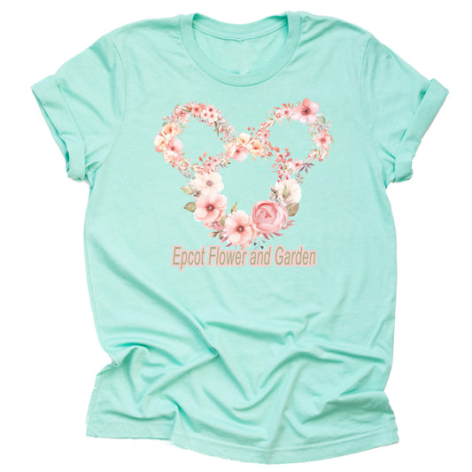 A short-sleeved unisex t-shirt in a mint color, featuring floral graphics arranged in the shape of mickey with the Epcot logo with the text 'Epcot Flower and Garden' on the front.