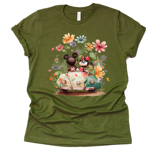 A olive-colored unisex t-shirt featuring an illustration of Mickey and Minnie Mouse with flowers and a vehicle.