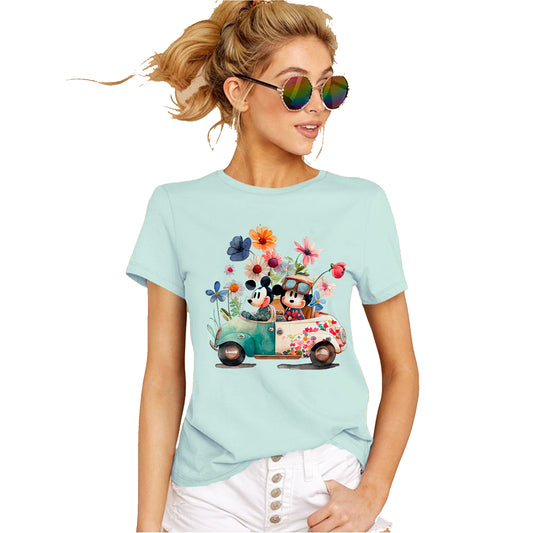 A women wearing mint-colored unisex t-shirt featuring an illustration of Mickey and Minnie Mouse sitting a Volkswagen in garden attire, surrounded by floral elements and a whimsical design.